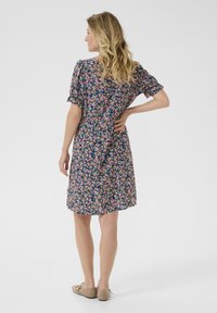 Rochie florală în nuanțe de bleumarin, decorată cu flori mici de roz, galben și alb. Mâneci scurte, talie elastică, lungime până la genunchi și material moale. Design casual.