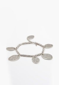 Silverfärgad kedjearmband med fem oregelbundna, hamrade ovala berlocker på en vit bakgrund.