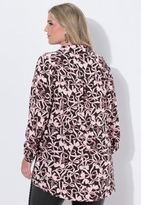 Blusa a maniche lunghe nera con un motivo floreale astratto rosa. Presenta polsini con bottoni e una vestibilità comoda, che arriva a metà coscia. Tessuto dalla texture liscia.