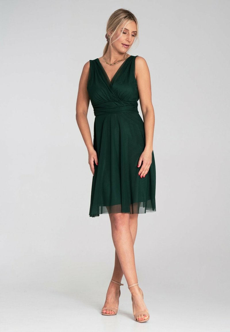 Dunkelgrünes, knielanges Kleid mit V-Ausschnitt und tailliertem Oberteil. Es hat einen strukturierten Tüllrock, ärmelloses Design und eine Wickeldetail an der Taille.