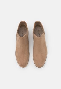 Botas de tobillo de ante color marrón claro con un acabado suave, acentos elásticos en los laterales y una suela cosida. Etiqueta de tamaño "37" visible en el interior.
