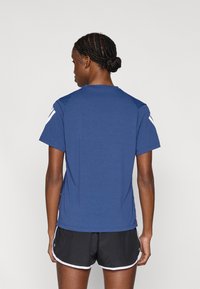 Ναυτικό μπλε αθλητικό t-shirt με κοντά μανίκια, κατασκευασμένο από αεριζόμενο ύφασμα, με λευκές λεπτομέρειες στους ώμους και άνετη εφαρμογή.