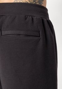 Zwarte joggerbroek van een soepele katoenmix, met een elastische tailleband en een klein achterzakje met een gestikte rand.