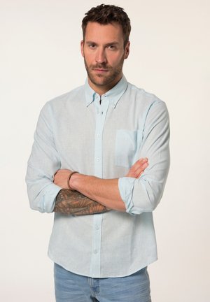 Lichtblauwe button-up shirt met een enkele borstzak, lange mouwen opgerold bij de manchetten, gemaakt van een gestructureerde stof, gecombineerd met spijkerbroeken.