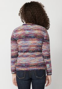 Pull en tricot avec un motif multicolore aux nuances de violet, bleu et rose. Il possède des manches longues et un col rond. Fini en tissu texturé.