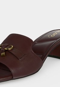 Mule en cuir marron à bout ouvert avec détail d'anneau doré et nœud, semelle intérieure rembourrée et talon bloc bas.