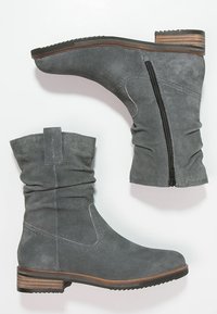 Bottines en suède gris avec un design doux, fermeture éclair latérale et un talon en bois empilé. Tige texturée et semelle lisse pour une bonne adhérence.