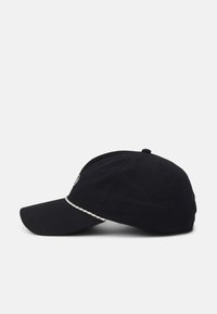 Gorra de béisbol negra hecha de tela, con visera curvada y un ribete decorativo blanco en la parte frontal. Incluye detalle de logo bordado.