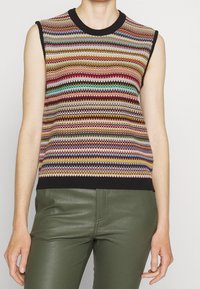 Haut sans manches en maille avec des rayures horizontales multicolores, col et ourlet côtelés noirs, associé à un pantalon en cuir vert.