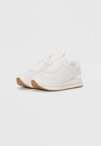 Pair of white lace-up sneakers with light brown ridged soles and subtle stitching details on a plain white background.