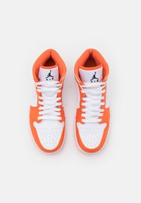 Högsneakers i vitt läder med orange detaljer. Perforerad tå, vita snören och svart logotyp på tungan. Texturerad innersula.
