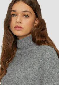 Hellgrauer Rollkragenpullover mit einer weichen, strukturierten Oberfläche. Verfügt über einen hohen Kragen und gerippte Ränder. Minimalistisches Design, vielseitiger Stil.