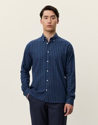 Sötétkék, hosszú ujjú ing, fehér függőleges csíkokkal, gallérral és gombos légzéssel, texturált anyagból készült.