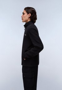 Black fleece jacket with a high collar and zip closure. Features side pockets and a logo on the chest. Textured, soft fabric.