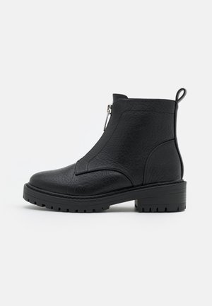 Bottine noire en cuir texturé, dotée d'une fermeture éclair latérale, d'un talon robuste et d'une semelle rugueuse pour une meilleure traction.