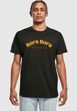 Sort bomulds t-shirt med "Bora Bora" i fed gul skrift og "FRANSK POLYNESIEN" nedenunder i mindre rød tekst. Standard pasform.