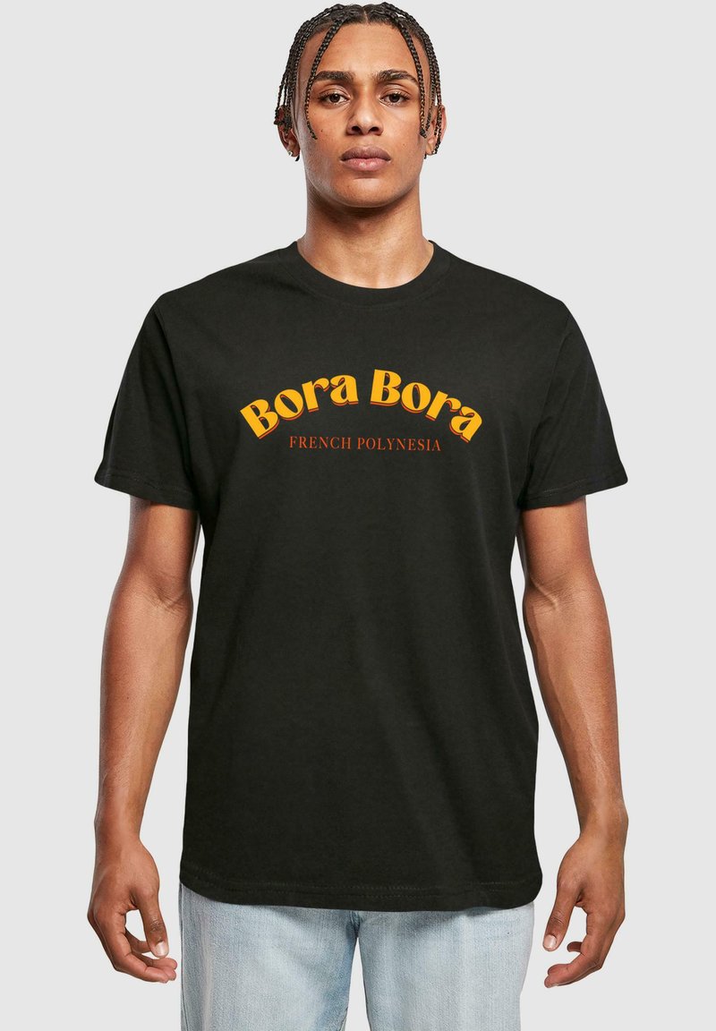 Melnā kokvilnas T-krekls ar uzrakstu "Bora Bora" bold dzeltenā rakstībā un "FRENCH POLYNESIA" zemāk mazākā sarkanā tekstā. Standarta izmērs.