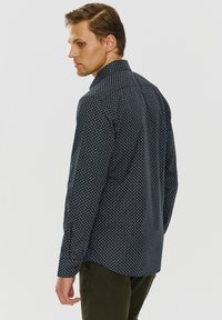 Navy blue koszula na guziki z małym geometrycznym wzorem, długimi rękawami i standardowym kołnierzykiem, wykonana z lekkiego materiału.