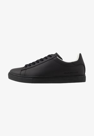 Zapatillas de cuero negro con una superficie lisa, punta redondeada y interior blanco. Presentan cordones negros y una suela de goma texturizada.
