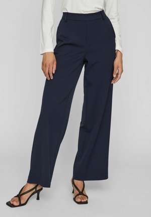 Navy wide-leg trousers made of smooth fabric with a high waist, featuring belt loops and side pockets. Paired with black heeled sandals.