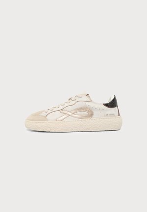 Λευκό χαμηλό sneaker με μύτη από κρεμ σουέτ, μεταλλική λεπτομέρεια βρόχου στο πλάι, μαύρη ταβανόπετρα φτέρνας και υφασμένο παχύ πέλμα.