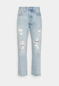 Ljust blå denimjeans med rak passform, som har slitna områden och fransade fållar, som visar en använd look med synliga revor.