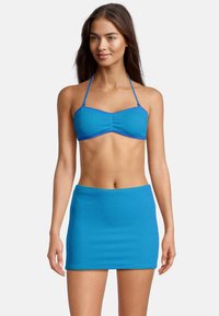 Haut de bikini texturé bleu avec jupe assortie. Le haut comporte des bretelles réglables ; les deux pièces ont une coupe ajustée et une texture côtelée.