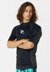 Sort kortermet rash guard med rund halsudskæring og et hvidt logo på brystet. Glat, strækbart stof.