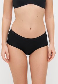 Black cotton hipster panties with a smooth texture, mid-rise waist, and seamless design. Features minimalistic style with no additional accents.