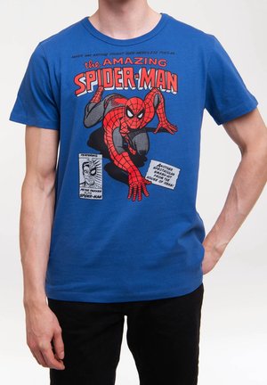Blaues T-Shirt mit einem grafischen Aufdruck von einem kauenden Spider-Man und Text, getragen von einer Person, die eine Hand in der Tasche und die andere herunterhängen hat.
