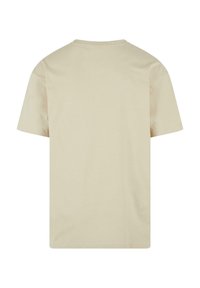 T-shirt en coton beige à manches courtes, col rond et coupe décontractée. Texture lisse sans motifs ni graphiques visibles à l'arrière.