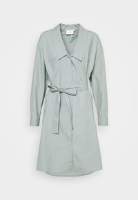 Svetle zelené šaty z měkké tkaniny, s velkým límcem, zapínáním na knoflíky vpředu, dlouhými rukávy a zavazovacími páskem v pase.