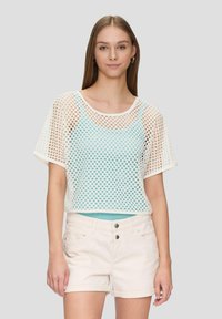 Geknipte mesh top met wit ruitpatroon; blauwe binnenlaag, korte mouwen, ronde hals; gecombineerd met lichtbeige shorts.