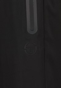 Zwarte stoffen broek met een verticale grijze accent, subtiel logo in zwart, en een soepele textuur. Eenvoudig ontwerp zonder aanvullende versieringen.