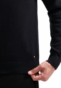 Marineblauwe trui gemaakt van fijn gebreide stof, met een geribbelde zoom en manchetten. Kleine merkaaccent in de linkerbenedenhoek. Eenvoudig, aangesloten ontwerp.