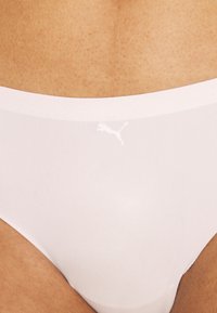 Bijela bešavna tanga izrađena od glatkog, laganog materijala sa malim, diskretnim bijelim Puma logom na prednjem pojasu.