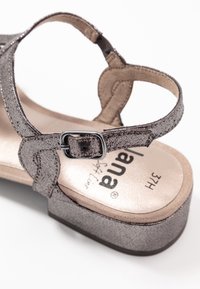 Sandale grise métallisée avec une sangle à boucle réglable et une semelle intérieure rembourrée étiquetée "Lana Soft Line", taille 37H, sur un fond blanc.