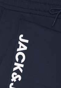Navy blue sweatpants made of soft fabric, featuring a white "JACK&JONES" logo printed vertically on the side and an adjustable drawstring waist.