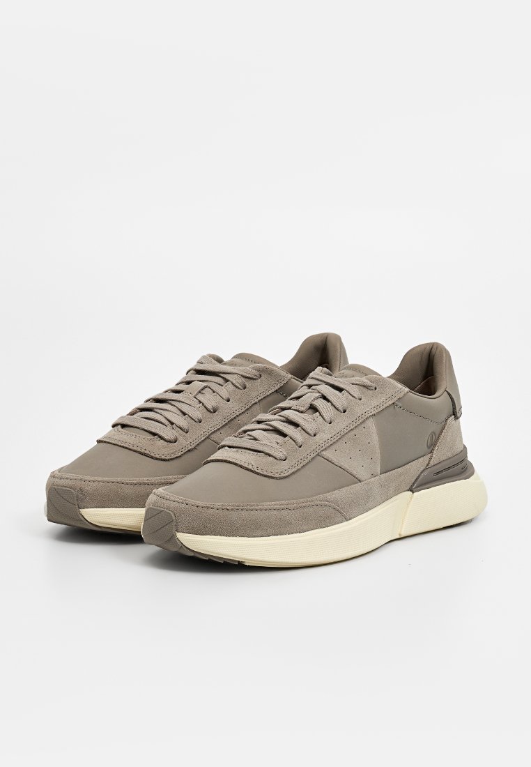 Sneakers in suede grigio con design a basso, caratterizzati da una tomaia testurizzata, punta arrotondata e una suola a contrasto di colore crema.