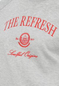 Šedá mikina s červeným vyšitým textom: "THE REFRESH" a "Soulful Origins," s kruhovým emblémom a "Est. 2017." Mäkko štruktúra.