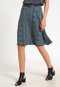 Jupe mi-longue à motifs floraux en vert foncé avec des accents bleu clair, faite d'un tissu léger, avec un design évasé et une taille.