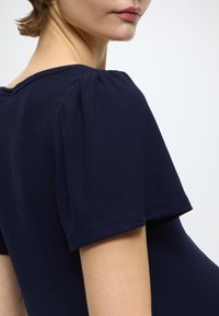 Top azul marino de canalé con mangas cortas abullonadas y escote ancho, que presenta una textura suave y detalles de costuras limpias.