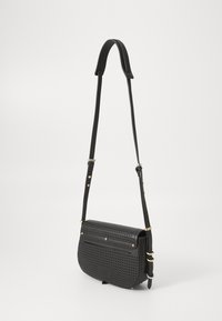 Borsa a spalla in pelle nera forata con accenti dorati, forma arrotondata, tracolla regolabile e chiusura anteriore con due bottoni a pressione.