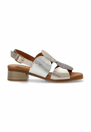 Sandalias con tacón bajo en bloque, con tiras de cuero metálico plateado y bronce, recortes redondeados y detalles remachados. Plantilla de cuero marrón suave.