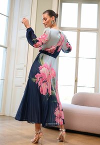 Faltenrock Midi-Kleid mit floralem Design in Pink und Grün auf navy Hintergrund, mit transparenten langen Ärmeln und gebundenem Taillenbereich.