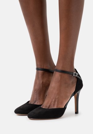 Chaussures à talons hauts en suède noir avec un design à bout pointu, dotées d'une fine bride réglable à la cheville et d'un talon lisse contrastant.
