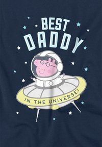 Navy-Blaues Shirt mit einem Cartoon-Schwein im Raumanzug, das sich in einer fliegenden Untertasse befindet, mit dem Text "Bester Papa im Universum!" und Sternakzenten.