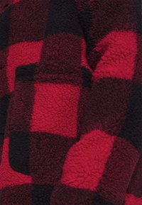 Red and black checkered fleece fabric with a soft, textured surface. Features large squares and a plush feel, ideal for warmth.