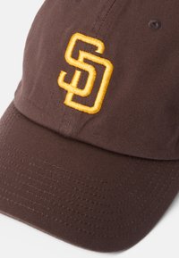 Brączowy czapka baseballowa o strukturalnym designie z haftowanym żółtym logo "SD". Materiał ma teksturowane wykończenie z widocznymi szwami.
