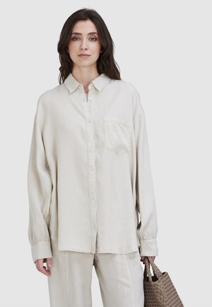 Licht beige, lang-ennstrijk shirt met knoopsluiting aan de voorkant, borstzak en een ontspannen pasvorm, gemaakt van zachte stof met een gladde textuur.